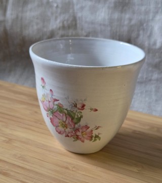 Hvit kopp uten hank med blomst